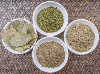 Rosemary, parsley, bay leaves and thyme in white bowl over wicker background