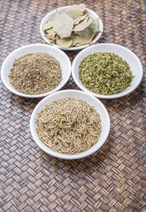 Rosemary, parsley, bay leaves and thyme in white bowl over wicker background
