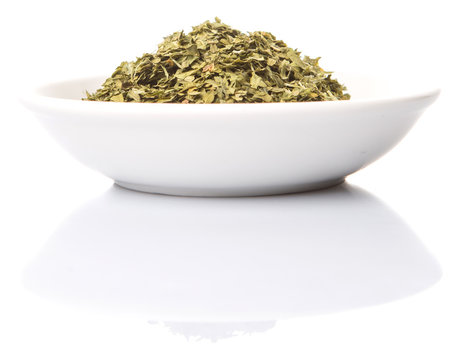 Dried parsley herbs in white bowl over white background