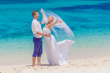 Fototapeta na wymiar bride, groom and guests enjoying beach wedding in tropics, on we