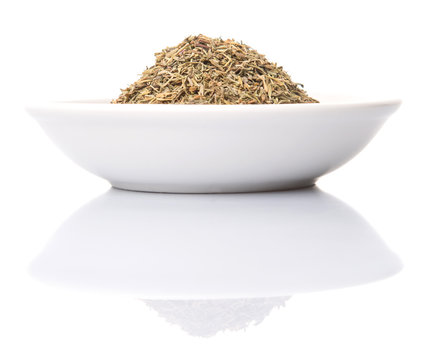 Dried thyme herbs in white bowl over white background