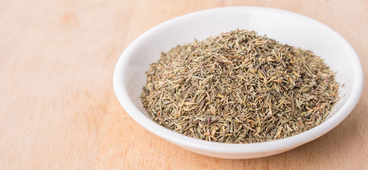 Thyme herb in white bowl over wooden background