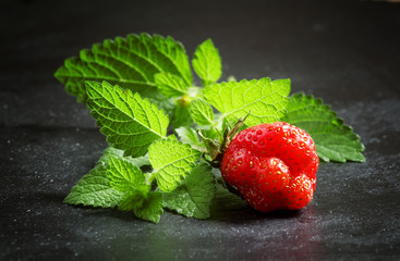 Fresh strawberries with mint leaves on a dark gray background, s