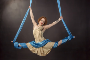 Young gymnast doing exercise on aerial silks