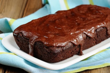 Dark chocolate cake with leaky chocolate icing in white plate
