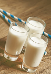 Three glasses of fresh milk on old wooden table in rustic style,