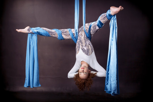 Young gymnast doing exercise on aerial silks