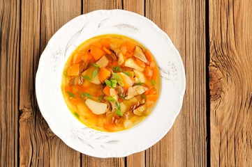 Porcini mushroom soup with potato and carrot in white plate on w
