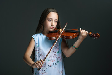 The young girl playing the violin on the dark background
