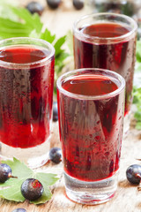 Fresh black currant juice with berries in glasses on an old wood