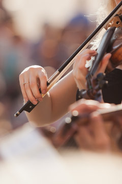Hands of the girl playing the violin in the orchestra