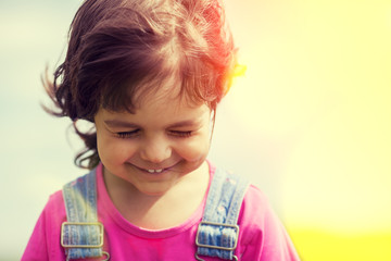 Portrait of happy smiling little girl walking on sunny windy day