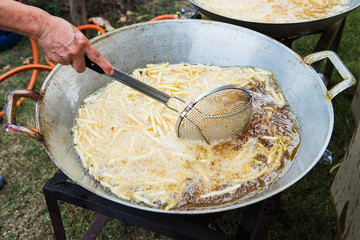 A strainer full of french fries is lowered into the boiling oil.