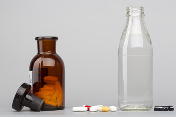 Bottle of water, a glass medicine bottle and pills