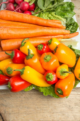 Fresh carrots, lettus, bell peppers, and radishes on weathered w