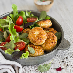 chicken cutlets and fresh vegetable salad in a vintage pan on a light wooden background