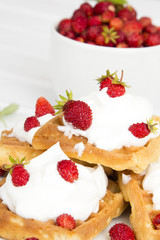 waffles with wild strawberries and whipped cream on white table