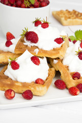 waffles with wild strawberries and whipped cream on white table