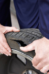 Close Up Of Mechanic Examining Damaged Car Tyre