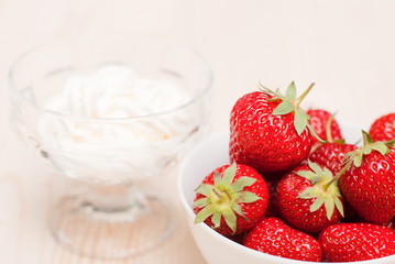 Strawberries in a white bowl on a light table, on the background