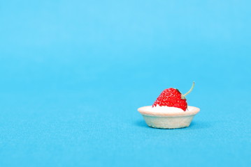 Tartlets with strawberry and cream on a blue background, side vi