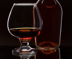 Glass of whiskey with bottle, on dark background