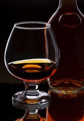 Glass of whiskey with bottle, on dark background, selective focu