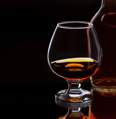 Glass of whiskey with bottle, on dark background, selective focu