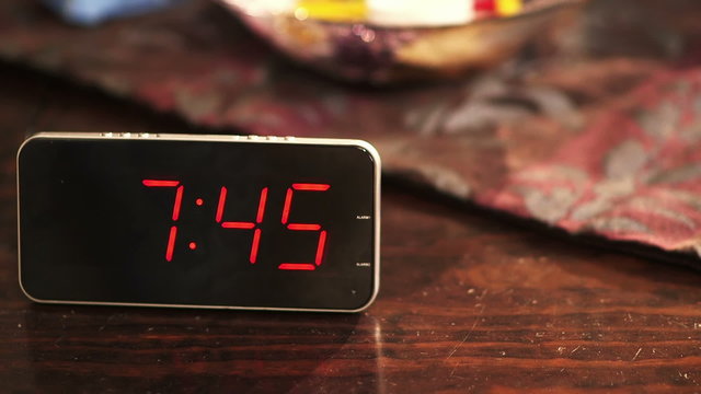 Close-up of a digital clock placed on wooden table when the time's passing.