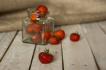 Stawberries in a jar and spilt on table