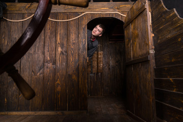 Young Man Peering Out From Cabin of Wooden Ship © kolotype