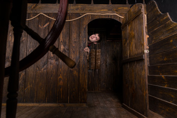 Young Man Peering Out Doorway of Wooden Ship © kolotype