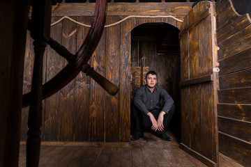 Young Man Peering Out From Cabin of Wooden Ship © kolotype