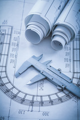 Rolled construction drawings and stainless slide caliper on blue