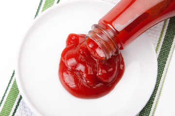 Pouring Ketchup from the Bottle – Ketchup pours from the bottle onto a white plate. Green stripes in background.