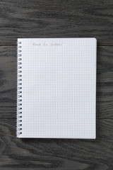 back to school phrase in notepad with chequered pages on gray