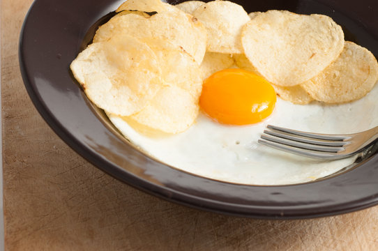 view of a fried egg served on dark dish with fries