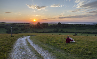 woman and dog enjoying sunset