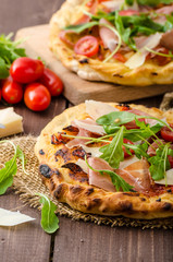 Italian pizza with parmesan cheese, prosciutto and arugula