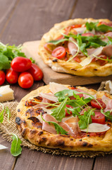 Italian pizza with parmesan cheese, prosciutto and arugula