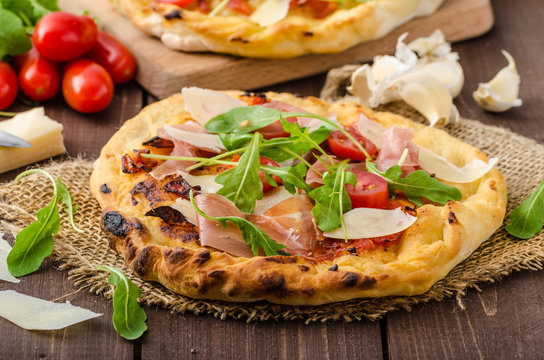 Italian pizza with parmesan cheese, prosciutto and arugula