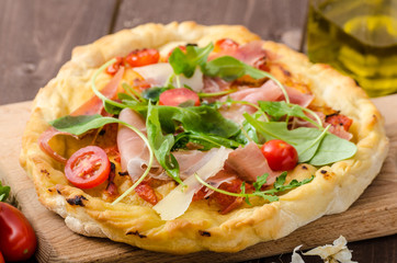 Italian pizza with parmesan cheese, prosciutto and arugula