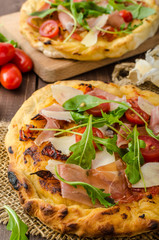 Italian pizza with parmesan cheese, prosciutto and arugula