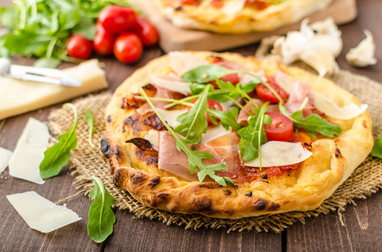 Italian pizza with parmesan cheese, prosciutto and arugula