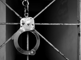 Handcuff shackle on  steel cage in front of the dark way