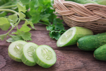 Fresh cucumber and slices on wooden table