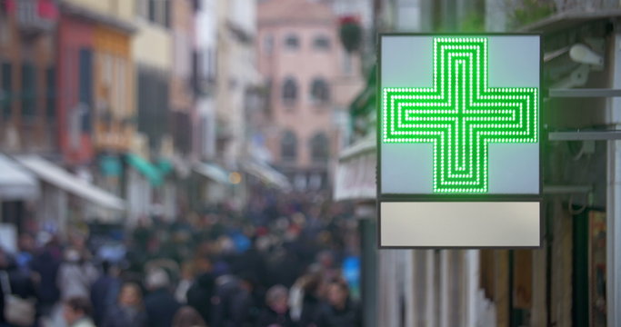 Pharmacy sign with green cross in busy street