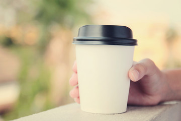 Hand holding take away coffee cup with retro filter effect