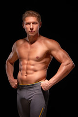 Young muscular handsome shirtless sportsman demonstrating muscles
