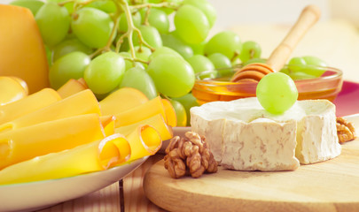 Still life with cheese, walnuts, honey and grapes